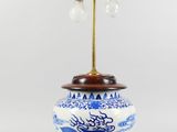 un vase bleu et blanc posé sur un socle sur lequel est posée une lampe
