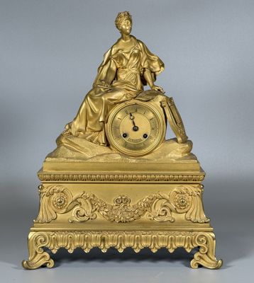 l'image d'une horloge en or sur laquelle est assise une femme