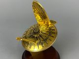 a gold sundial on a wooden base with a white background
