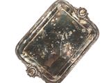 un plateau en argent comportant un miroir, posé sur une surface blanche