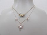 two necklaces with pearls and a butterfly on a mannequin