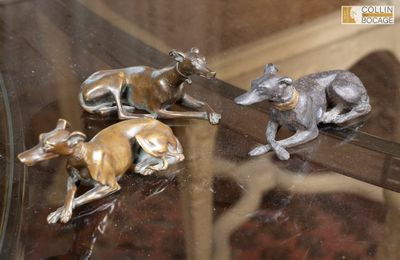 trois figurines de lévriers posées sur une table en verre