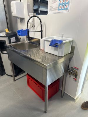un évier en inox dans une cuisine avec des poubelles rouges posées sur le plan de travail