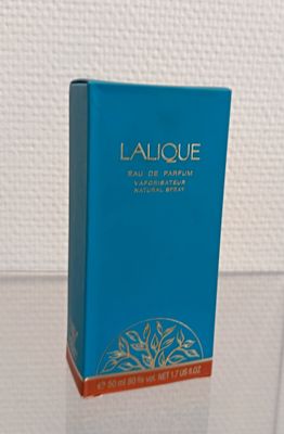 une photo d'un flacon de parfum posé sur une table en verre