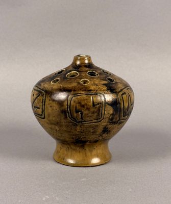 a brown vase with a design on it on a gray surface