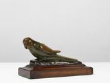 une sculpture en bronze représentant un oiseau, posée sur un socle en bois