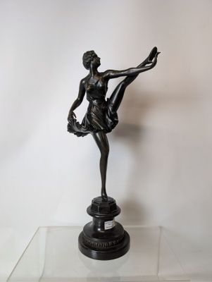 statue en bronze représentant une femme tenant une ballerine sur une table en verre