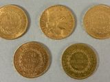 four different types of gold coins on a white surface