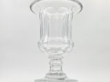 a clear glass vase on a stand on a white background