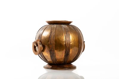 a gold vase sitting on a white surface