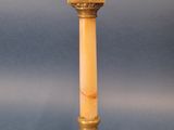 an antique brass candle holder with a marble base on a blue background