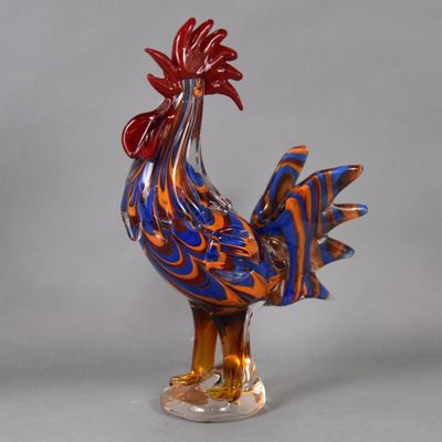 a glass rooster that is standing on a base