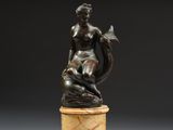 une statue en bronze représentant une femme assise sur un socle en marbre