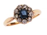 gros plan d'une bague avec un saphir bleu entouré de diamants blancs