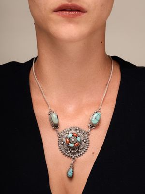 La femme porte un collier orné de perles de turquoise.