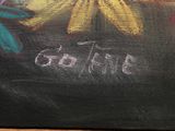 a painting of flowers painted on a blackboard on a table