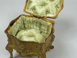 a gold box with a green cushion inside of it