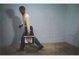 a man that is walking with a television in his hand