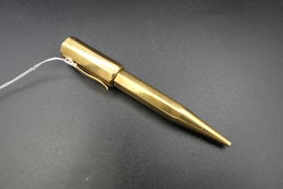 un stylo de couleur dorée posé sur une table, à côté d'une ficelle