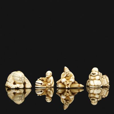 four carved ivory figurines of buddhas sitting on a rock
