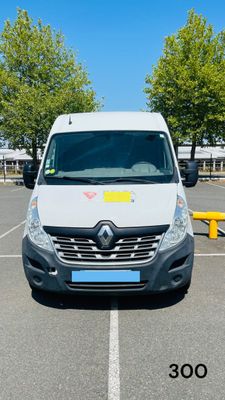 une camionnette blanche garée sur un parking avec des arbres en arrière-plan