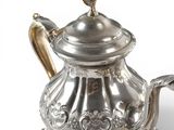 a silver tea pot with a bird on top of it