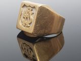 a close up of a gold ring with a crest on it