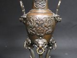 a bronze vase that is sitting on a stand