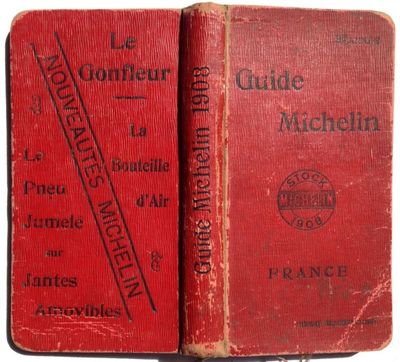 an old red book sitting on top of a table next to another book