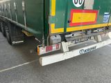 un camion-poubelle vert garé sur le bord de la route