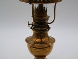une lampe ancienne en laiton, surmontée d'un abat-jour en verre blanc