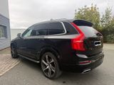 the rear end of a black volvo suv parked in front of a building