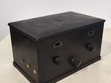 une vieille boîte en métal noir posée sur une table blanche