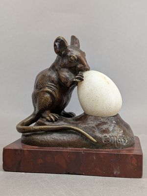 statue of a mouse with an egg on a rock