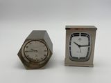 a small silver clock and a small silver clock on a white surface