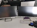 trois écrans d'ordinateur posés sur un bureau, avec un clavier et une souris