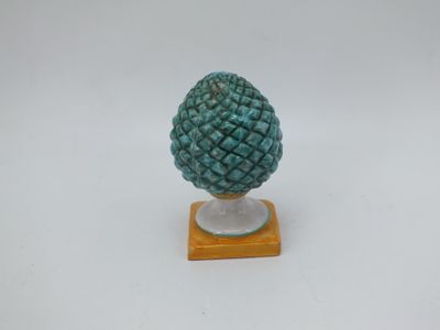 un gros plan d'une figurine représentant un ananas posée sur un socle en bois