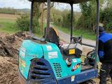 un homme debout dans la terre, à côté d'un tracteur