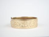 a close up of a gold bracelet on a white surface