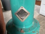 a green stove sitting on the floor next to a potted plant