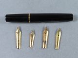 a close up of a fountain pen and five other pens on a table