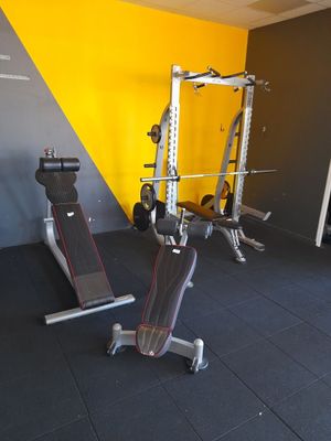 une salle de sport équipée d'un banc, d'haltères et d'autres appareils