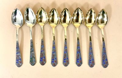 six cuillères en argent ornées de motifs bleus et dorés sont alignées en rangée