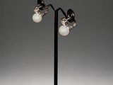 pair of silver and pearl earrings on a black metal stand