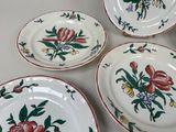 four plates with floral designs are arranged on a white surface