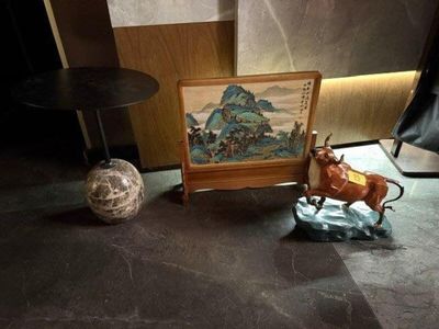 une petite statue représentant une vache, posée à côté d'une photo sur une table