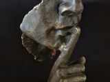 statue of a man with a bird on his head on a black surface