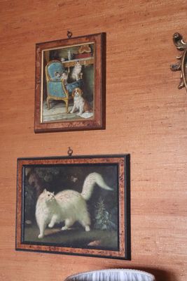 a cat that is standing in front of a painting on the wall