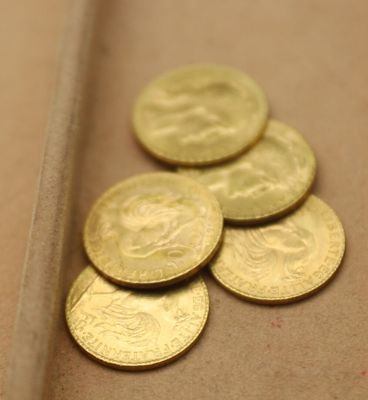 un tas de pièces d'or posées sur une table, à côté d'un couteau