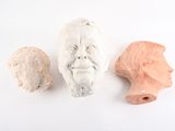 trois sculptures en argile représentant le visage d'un homme et la tête d'une femme